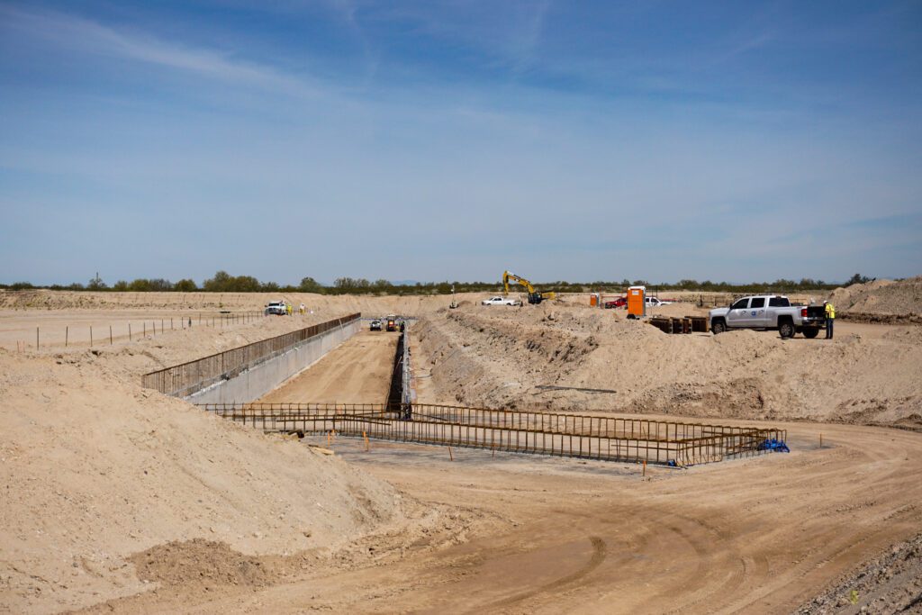 A construction site with ongoing civil engineering services infrastructure development, featuring excavation work and construction machinery under a clear sky.